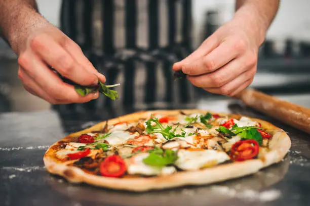 Close up of chef hands preparing pizza in Italian restaurant