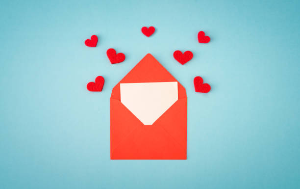 istock Red paper envelope with blank white note mockup inside and Valentines hearts on blue background 1291300064