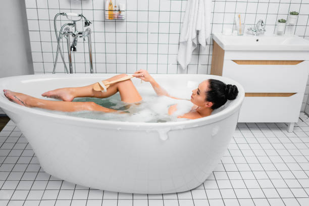 istock Brunette woman using brush in bathtub with lather in modern bathroom 1291301953