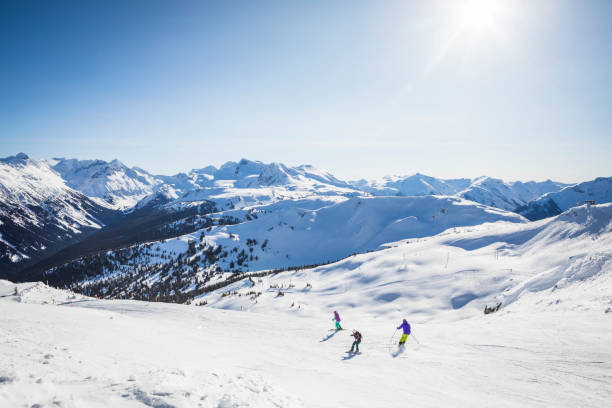 Group of friends skiing and snowboarding at Whistler Blackcomb ski resort. Beautiful sunny day in Whistler ski resort with skiers and snowboarder enjoying snow. whistler mountain stock pictures, royalty-free photos & images