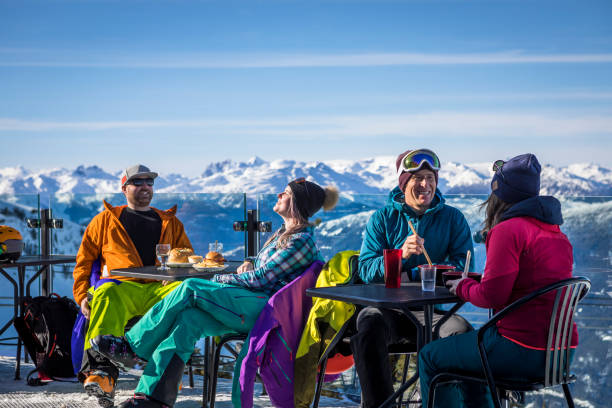 Group of friends enjoying apres-ski at top of Whistler mountain. Skiers having drinks at the top during their ski vacation in Whistler, Canada. whistler skiing stock pictures, royalty-free photos & images