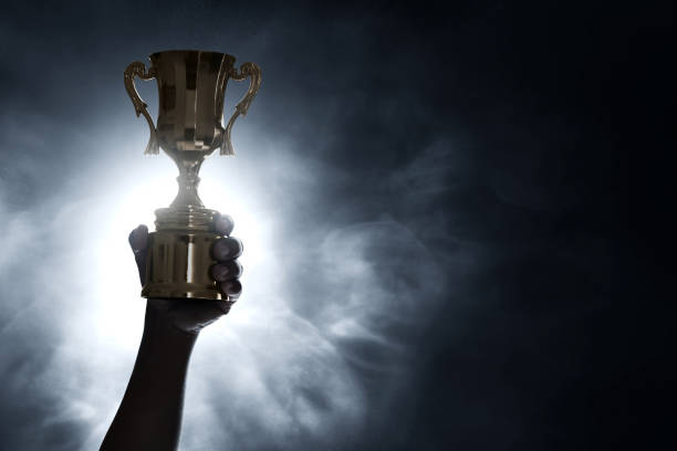 istock Man holding golden trophy cup 1291303779