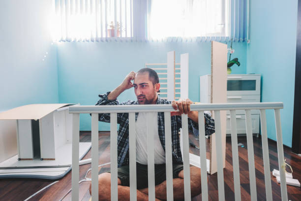 istock Young future father trying to assembling a baby crib in his home 1291304076