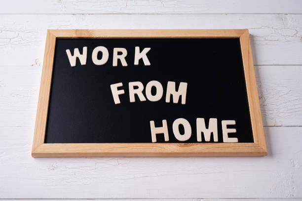 istock `Work from Home` words on a modern board on a white wooden surface, top view. Overhead, from above, flat lay. 1291312120