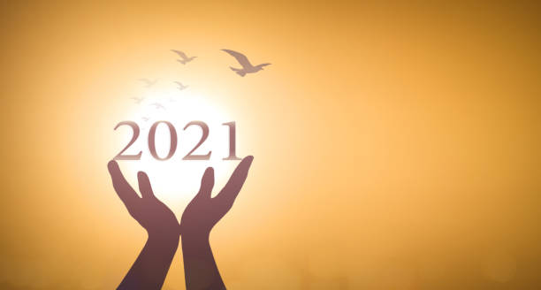 istock Hands show 2021 against birds flying on blurred yellow sunrise 1291316574
