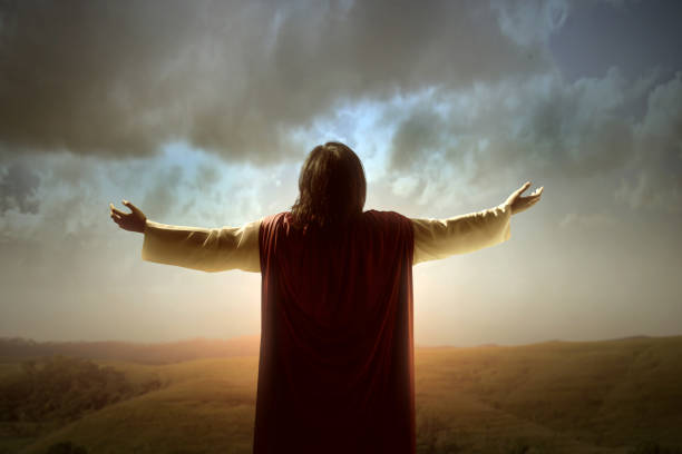 Rear view of Jesus Christ raised hands and praying to god Rear view of Jesus Christ raised hands and praying to god with a sunrise sky background jesus christ stock pictures, royalty-free photos & images
