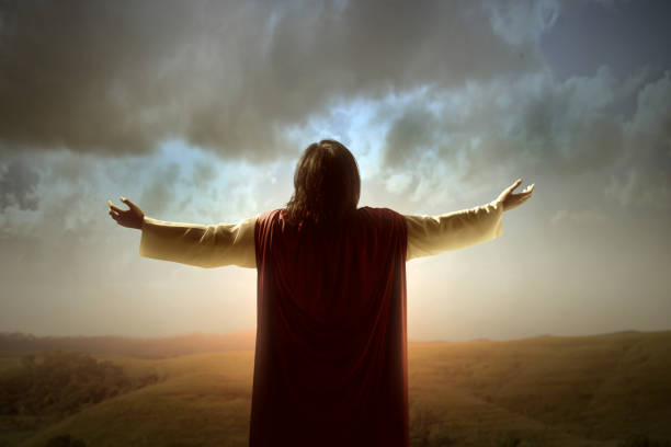 Rear view of Jesus Christ raised hands and praying to god Rear view of Jesus Christ raised hands and praying to god with a sunrise sky background god and jesus stock pictures, royalty-free photos & images