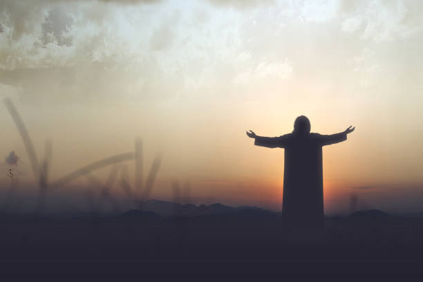 Rear view silhouette of Jesus Christ raised hands and praying to god Rear view silhouette of Jesus Christ raised hands and praying to god with a sunset sky background jesus christ photos stock pictures, royalty-free photos & images