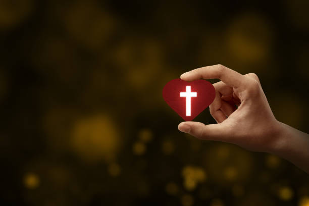 istock Human hand holding a red heart with a Christian cross 1291323088