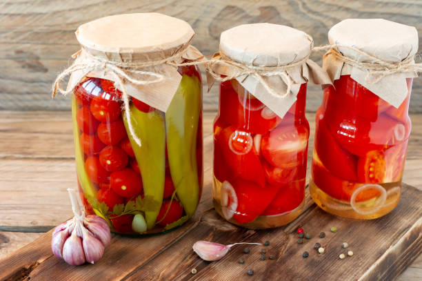 los tomates caseros se conservan en frascos de vidrio en cesta de mimbre blanco sobre fondo de madera - basket wicker marinated preserves fotografías e imágenes de stock