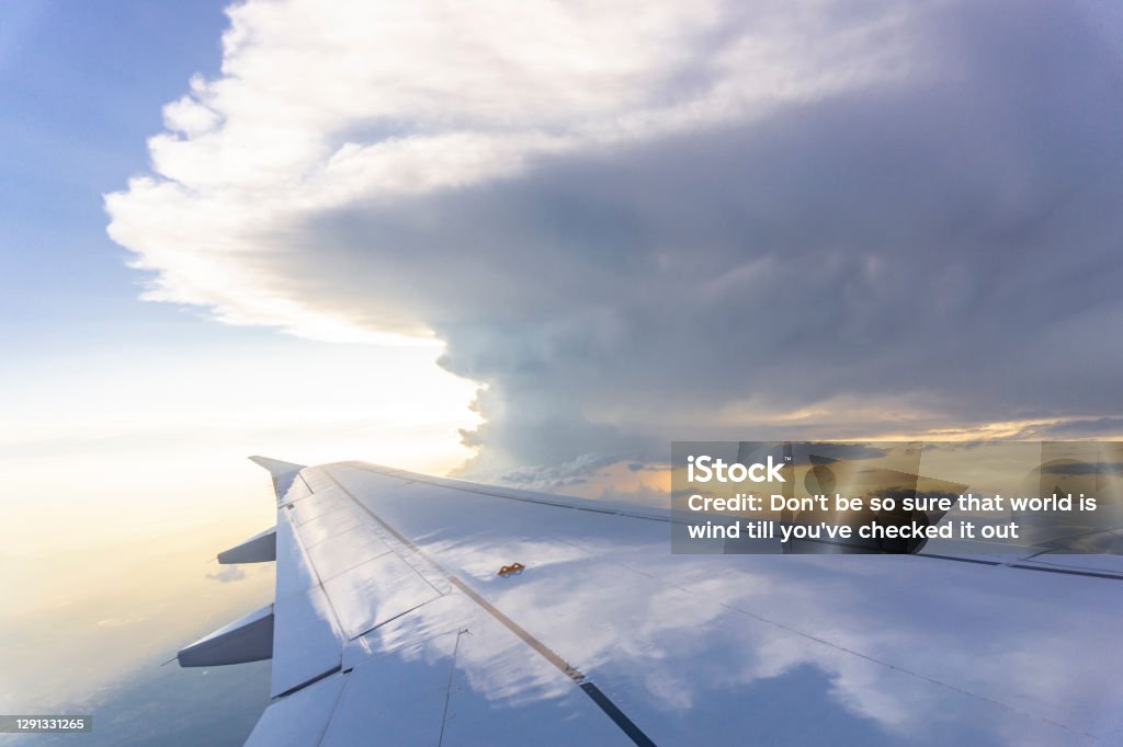 Sky scape view from clear glass window seat to the aircraft wing of the plane, traveling on the clouds and sunshine with blue sky Airplane Stock Photo