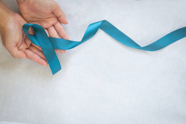 Hands holding teal color ribbon on white fabric with copy space. Ovarian Cancer Awareness, Gynecological, Uterine Cancer, Vulvar Cancer, Panic Disorder, Post Traumatic Stress Disorder (PTSD). Hands holding teal color ribbon on white fabric with copy space. Ovarian Cancer Awareness, Gynecological, Uterine Cancer, Vulvar Cancer, Panic Disorder, Post Traumatic Stress Disorder (PTSD). post traumatic stress disorder photos stock pictures, royalty-free photos & images