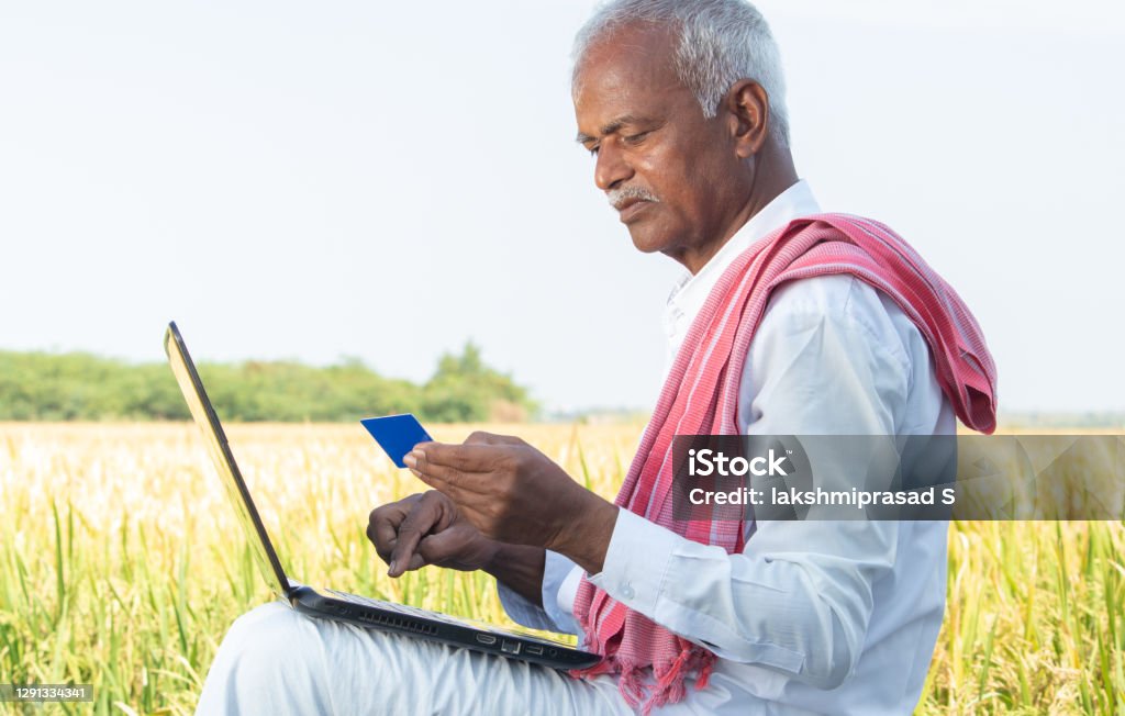 Indian farmer on laptop doing payment by using credit card - concept of rural people using technology, internet and lifestyle. Indian farmer on laptop doing payment by using credit card - concept of rural people using technology, internet and lifestyle Credit Card Stock Photo