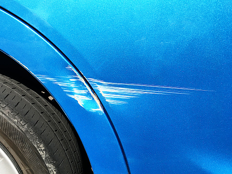 The body of the blue car is scratched and the paint is scraped.