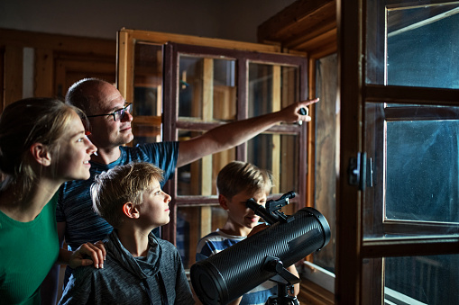 Father and three kids are using the astronomy telescope to observe the moon and the stars.
Nikon D850