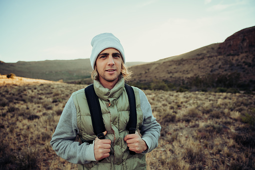 Happy male teen hiking in luscious mountain dressed warmly reading to exercise in fresh air . High quality photo