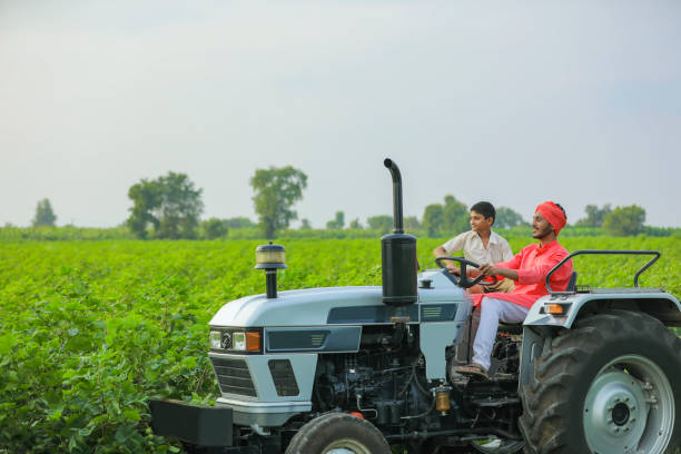istock Indian farmer with his little child working with tractor at field 1291340874