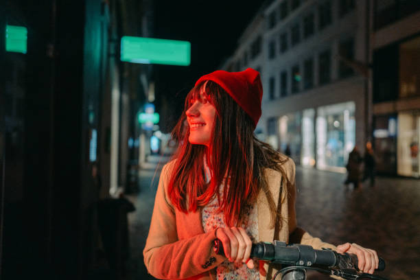 Late night ride Photo of a young woman riding an e-scooter late at night, in a downtown of a city; illuminated by the neon street lights. copenhagen photos stock pictures, royalty-free photos & images