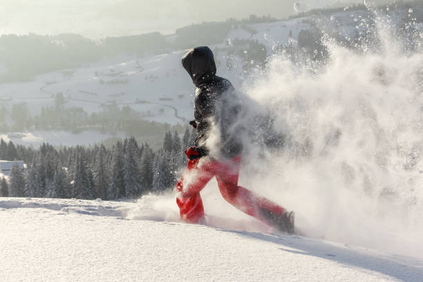 hombre feliz con capucha corriendo en nieve de polvo profundo con raquetas de nieve. la nieve está rociando y salpicando. - winter snowshoeing running snowshoe fotografías e imágenes de stock