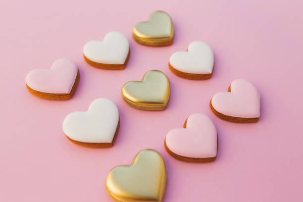 istock Pink background with sweet gingerbread heart cookies 1291345879