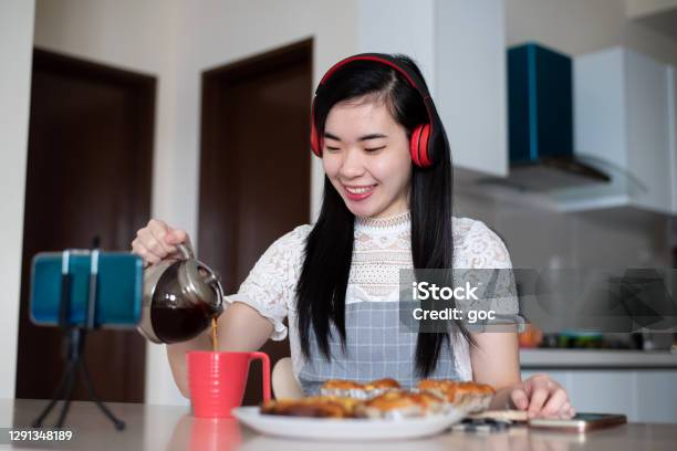 Young Asian Woman Having Tea Break With Homemade Pastries At Domestic Kitchen Stock Photo - Download Image Now