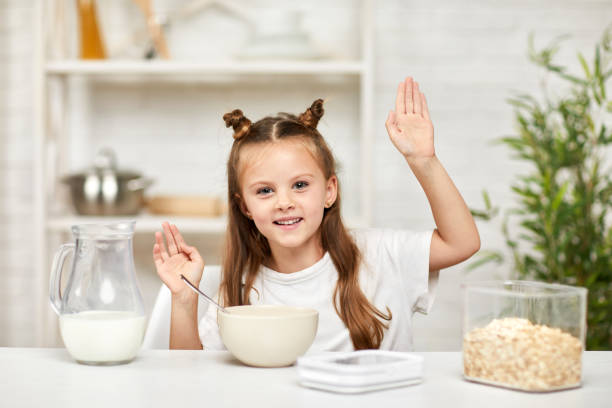 menina tomando café da manhã: cereal com o leite na cozinha. - healthy eating snack child domestic kitchen - fotografias e filmes do acervo