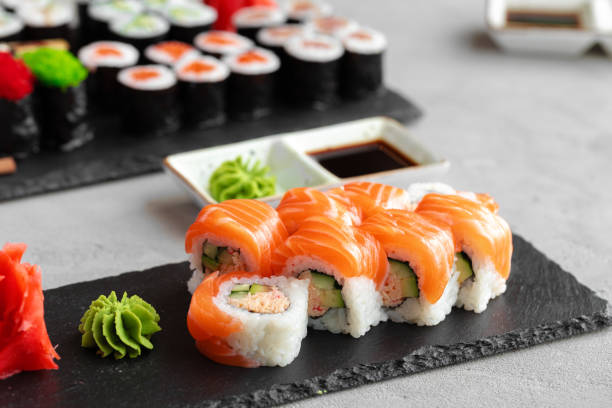 istock Sushi roll covered with fresh salmon served on plate 1291349655