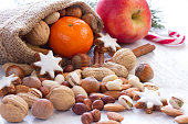 Nuts, fruits and cookies in jute sack, natural christmas food background