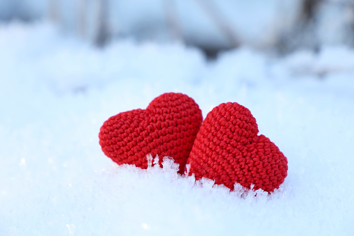 Two red knitted symbols of love, background for romantic greeting card