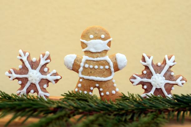 Gingerbread man with protective face mask, snowflakes and spruce twig