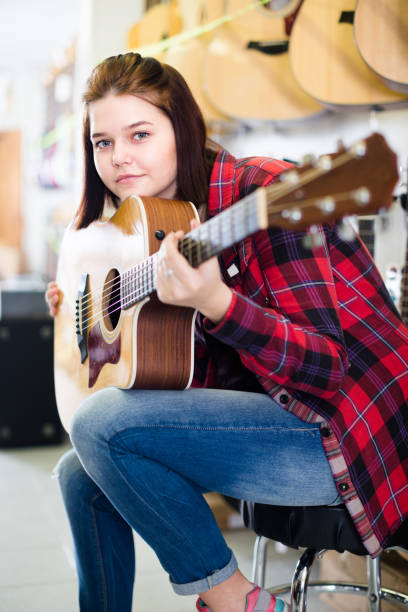 istock Young girl is deciding on acoustic guitar 1291353040