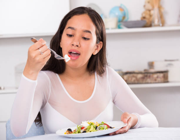 istock Positive young female eating salad 1291356315