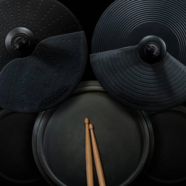 Black Electronic Drum Kit and Wooden Drumsticks Top view of a black electronic drum kit with cymbals and drums and a pair of wooden drumsticks, on a black background. Percussion instrument concept. snare drum photos stock pictures, royalty-free photos & images