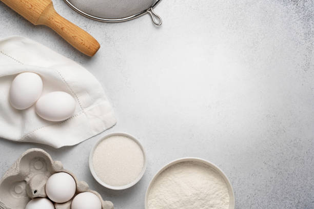 istock Wheat flour, sugar, sieve, rolling pin and white eggs on napkin on grey background. 1291361991