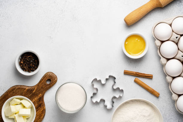 istock Flat lay with baking ingredients for gingerbread. Wheat flour, sugar, rolling pin, butter, honey, cinnamon sticks, cloves, cookie cutter and white eggs on grey background. 1291361998