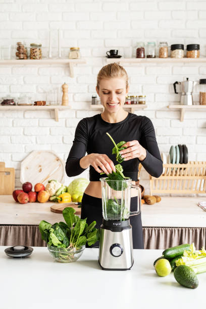 istock Young blond smiling woman making spinach smoothie at home kitchen 1291362814