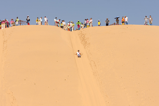 Kubuqi Desert, Inner Mongolia province / China - July 31, 2016: People sand dune sledging in Kubuqi desert in Inner Mongolia, China. Sand dune sledging is a popular tourist activity in Kubuqi desert