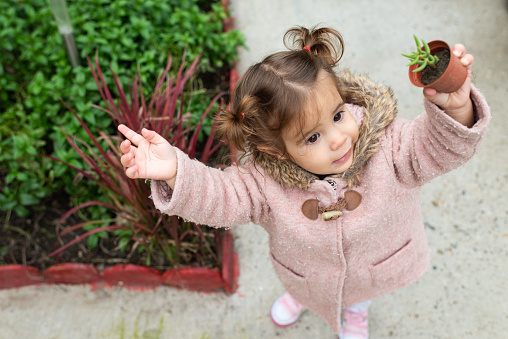 Beautiful girl holding baby plant outdoors.
