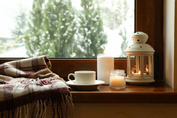istock Plaid, cup, candles and lantern on wooden windowsill 1291364431