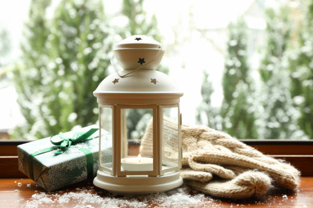 Lantern, gift and mittens on wooden windowsill