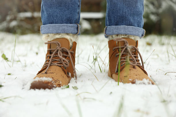 istock Woman in boots standing in snow with grass 1291364546