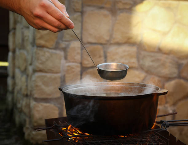 istock Man holding ladle over metal cauldron with soup on fire 1291364690