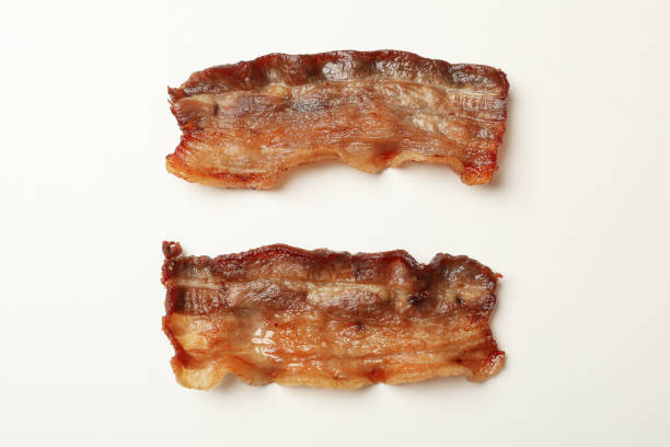istock Tasty fried bacon slices on white background 1291366115