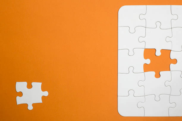 istock incomplete white puzzle with orange background. missing a piece to complete that is a little off. has space for text. copy for space 1291367543