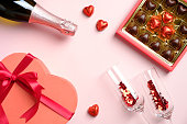 ハッピーバレンタインデーのコンセプト。フラットレイ、チョコレートのトップビューボックス、紙吹雪のシャンパングラス、ハート型の箱、シャンパンボトル