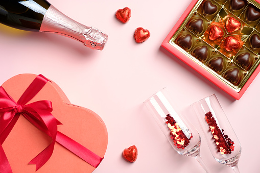 Happy Valentines Day concept. Flat lay, top view box of chocolates, champagne glasses with confetti, heart-shaped box, champagne bottle