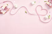 ピンクの背景にギフトボックスとバラの花とハートの形をしたリボン。ハッピーバレンタインデー、母の日、誕生日のコンセプト。ロマンチックフラットレイ構成。