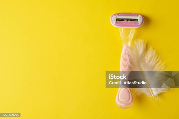 Razer And Feather On Yellow Background Space For Text Stock Photo - Download Image Now