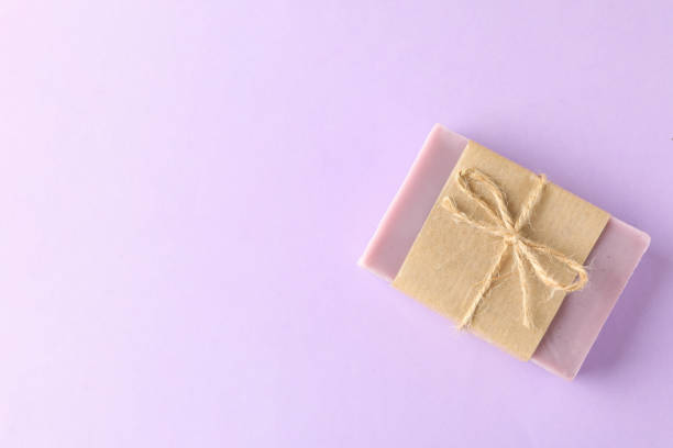 istock Piece of natural soap on violet background 1291369982