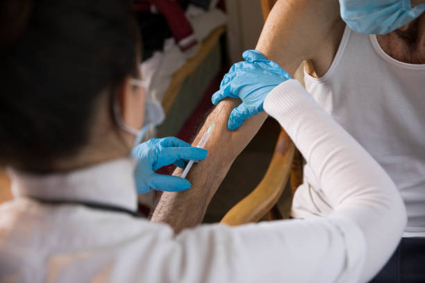 istock Senior man getting vaccinated by visiting nurse at home 1291371597